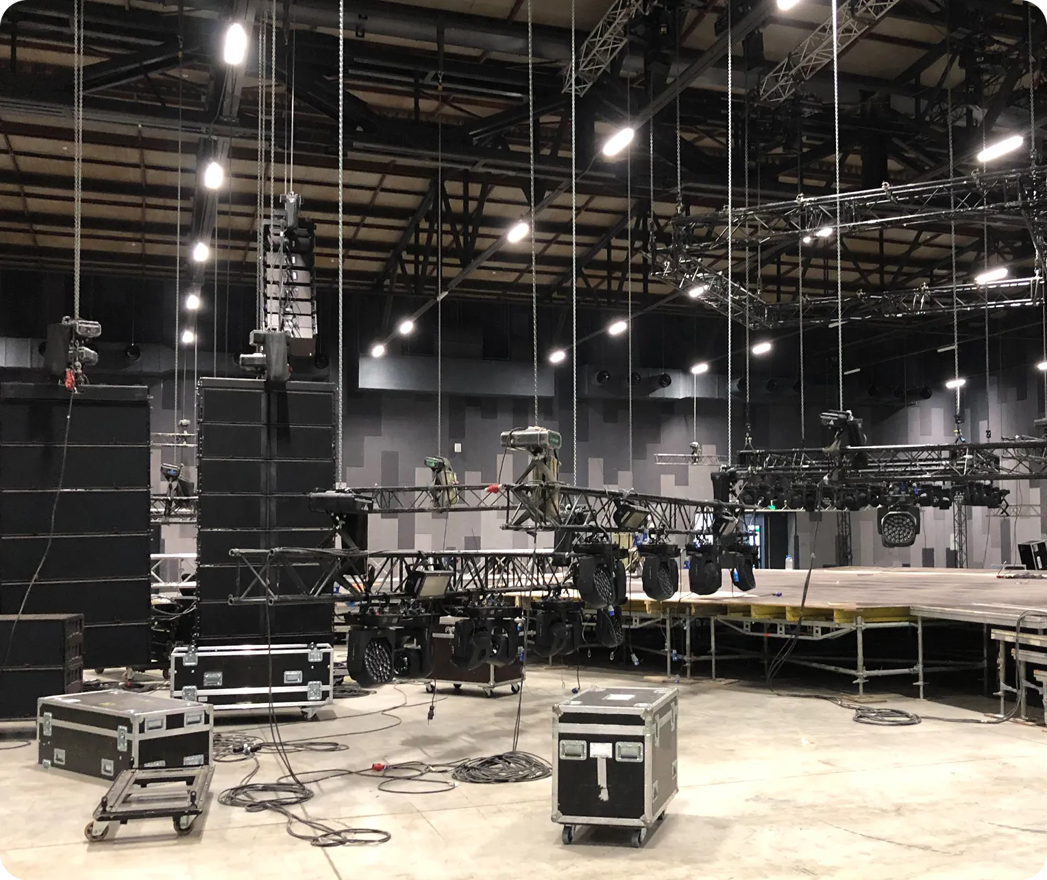 Large indoor arena setup with lighting and sound equipment; stage construction is in progress.